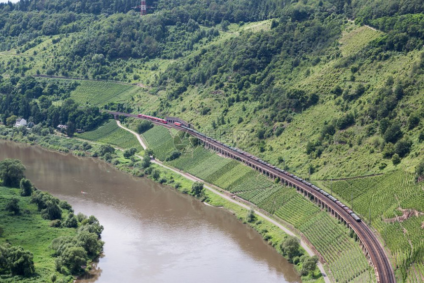客运列车和货在沿德国Moselle河的铁路轨迹上相通过图片