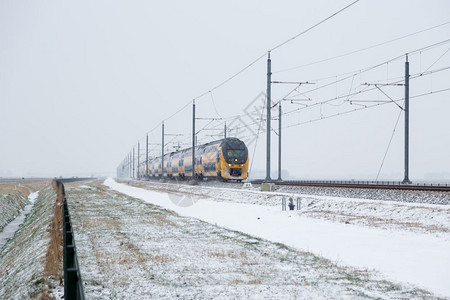 雪淋雨期间在荷兰农村冬季风景的火车图片