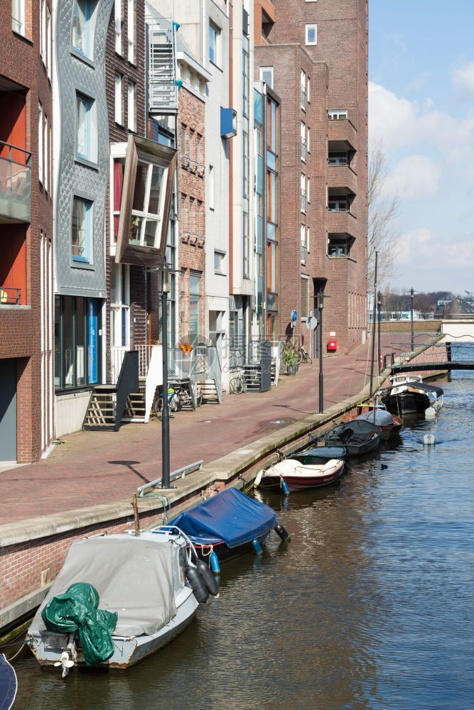 从阿姆斯特丹到的新住宅区沿一条有小船的运河图片