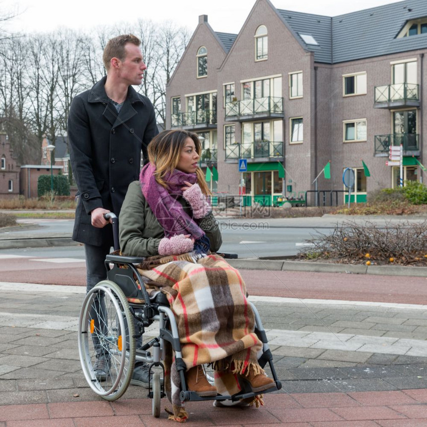 男人在荷兰村庄的斑马用轮椅推着一个女人图片