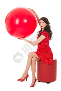 穿着红裙子的美女坐在脚凳上拿着一个大红气球背景图片