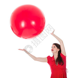 穿红裙子的美女抓住一个大红气球在头顶上背景图片