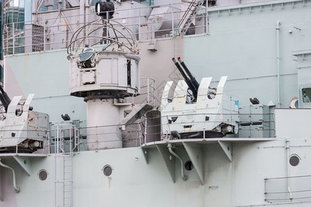军事战舰HMSBelfast在英国伦敦泰晤士河停泊的HMS贝尔法斯特战舰上的反飞机背景