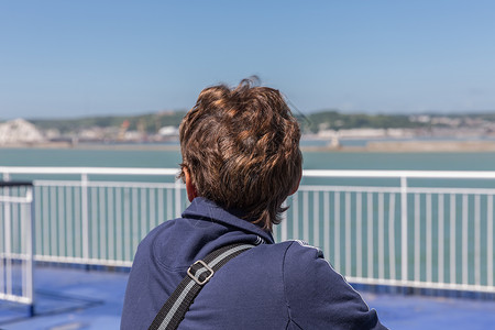 在渡轮上离开多佛的女人向后看英国海岸图片