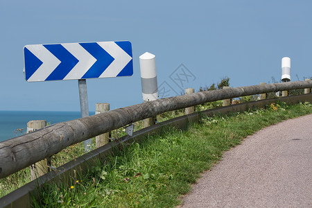 曲线蓝白法国诺曼底海岸附近有木制碰撞屏障和交通标志的公路法诺曼底海岸附近有交通标志的公路法诺曼底海岸附近有交通标志背景