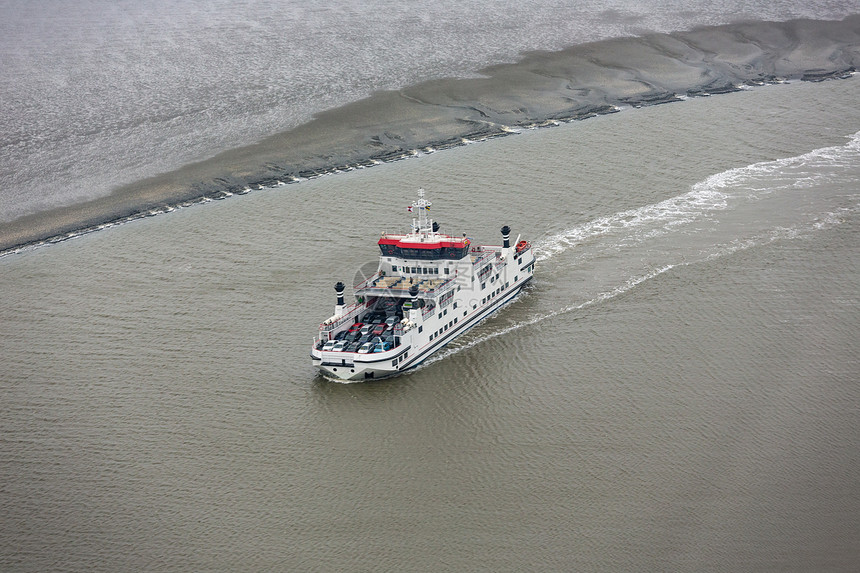 荷兰渡船在WaddenSea的荷兰渡船在WaddenSea通过沙岸之间的小通道低潮航行图片