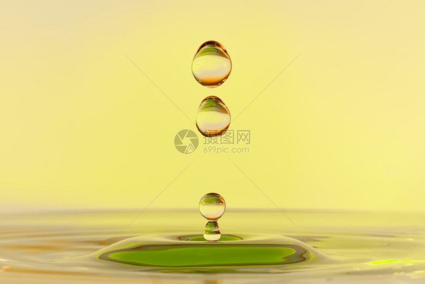 高速度水滴照片在黄色背景下落滴在黄色背景下坠图片