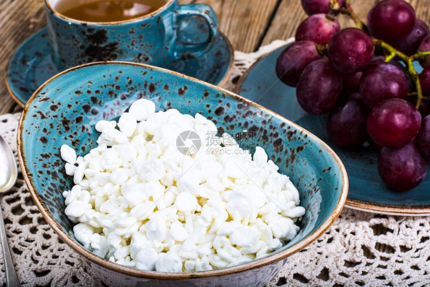 蓝色碗里的干奶酪和桌上的葡萄图片