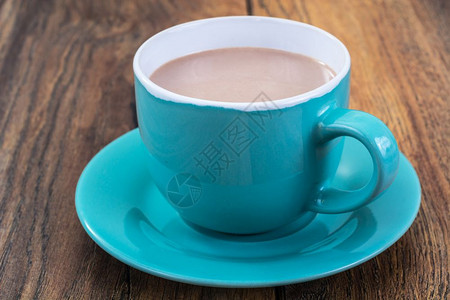 木制背景的蓝杯牛奶咖啡图片