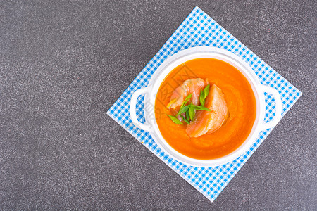 蓝色格子餐布上的胡萝卜南瓜奶油汤加鲑鱼图片