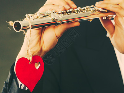 长笛演奏者情人节爱旋律概念长笛音乐演奏人吹风的音乐演奏者男手拿着乐器和红心关上门男吹风曲手拿着笛子和心爱旋律背景