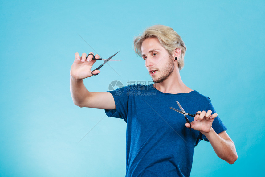感的男理发师拿着剪刀显示工作具正常和剪图片
