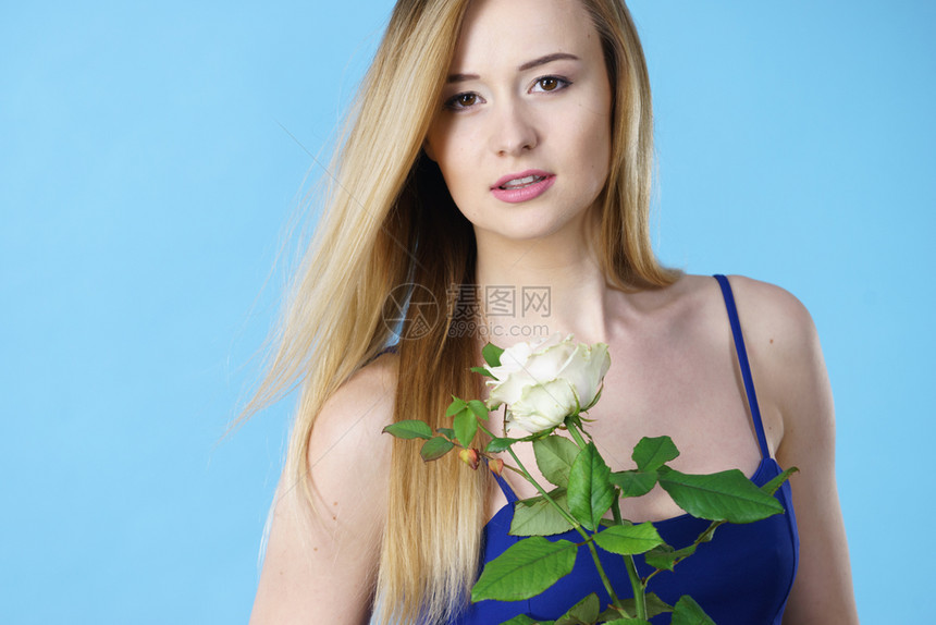 有魅力的金发年轻女子拿着白玫瑰花情人节和女礼物概念图片