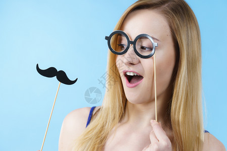 持嘉年华饰品眼镜和胡子在棍上玩的妇女图片