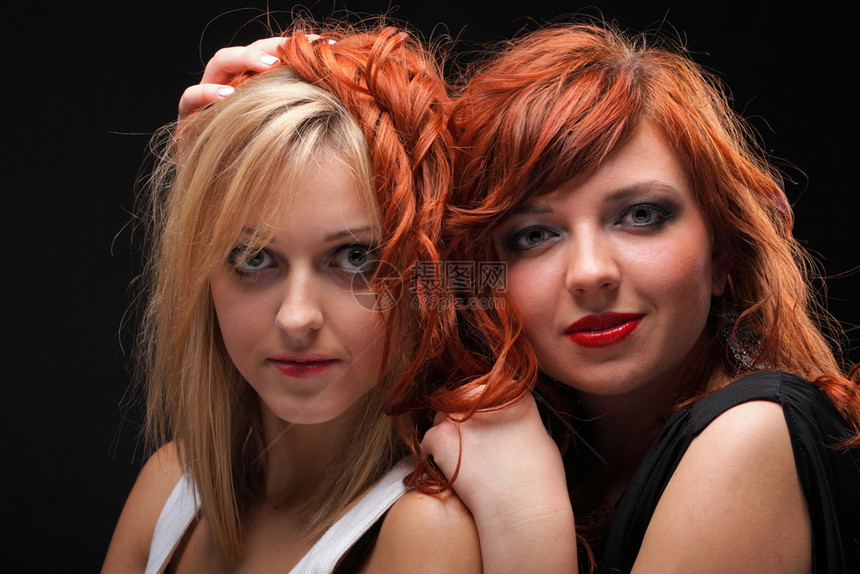 两个快乐的年轻女友金发红头黑背景图片