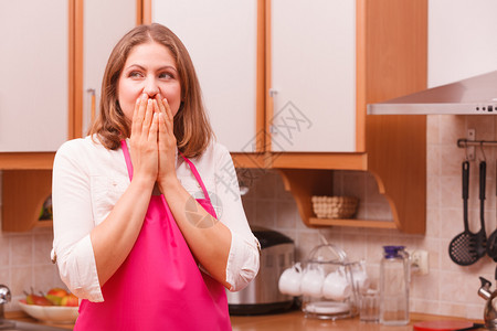 令人惊讶的是在厨房站着穿粉红色围裙的令人惊讶女士在厨房里惊讶的女主妇图片