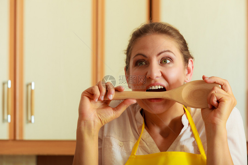 烹饪和做饭概念深思熟虑和困惑的女厨师主妇在房里拿着被咬的勺子在厨房里主妇拿着被拉的子在厨房里主妇拿着被咬的勺子在厨房里主妇拿着被图片