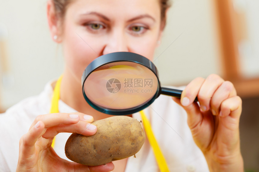 成年女用放大镜检查马铃薯食品图片
