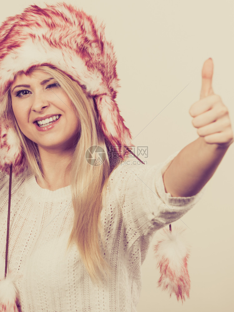 穿着冬季毛衣的女士穿着冬季毛衣的温暖帽子举起大拇指的手势图片