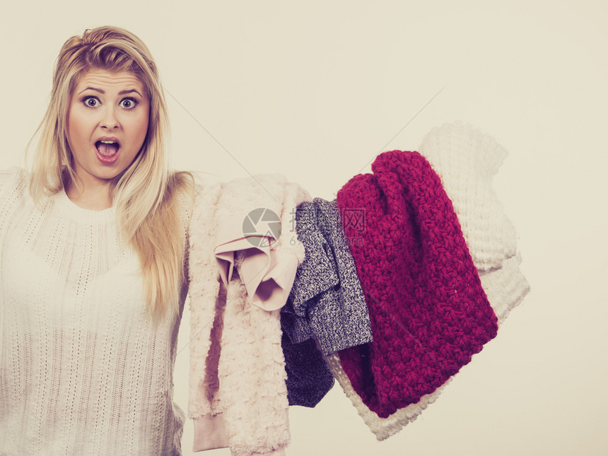 妇女拿着一堆冬衣不能决定穿什么衣服挑取冬概念图片