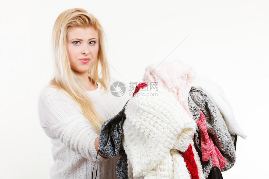时装服两难概念妇女拿着一大堆温暖的冬衣不能决定穿什么白灰色图片