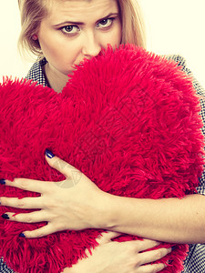 悲哀的年轻女人带着大红枕头的心型过滤照片背景图片