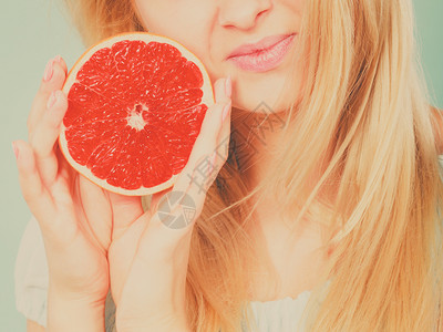 将一半红葡萄油柑橘水果握在近口手中的女积极孩健康饮食品暑假概念图片