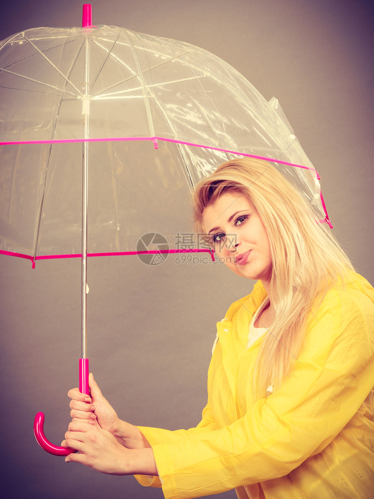雨天时心情良好金发妇女快乐穿着黄色雨衣拿透明伞戴雨衣伞穿雨衣的妇女快乐穿着透明伞图片