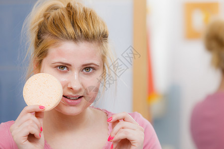 女在脸上洗凝胶手持海绵准备清洗皮肤女在脸上洗凝胶手持海绵背景图片