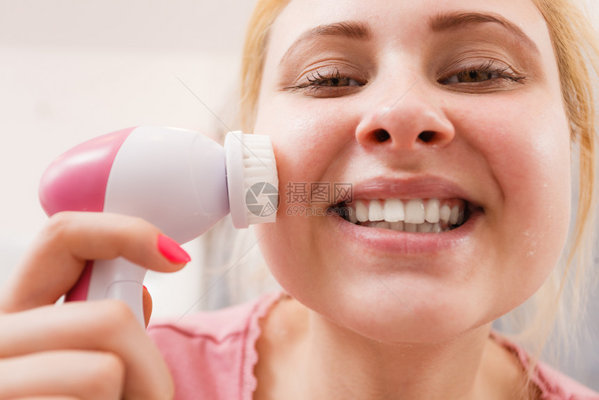 使用面部清洗刷机的快乐女人使用面部清洗刷子的快乐女人图片