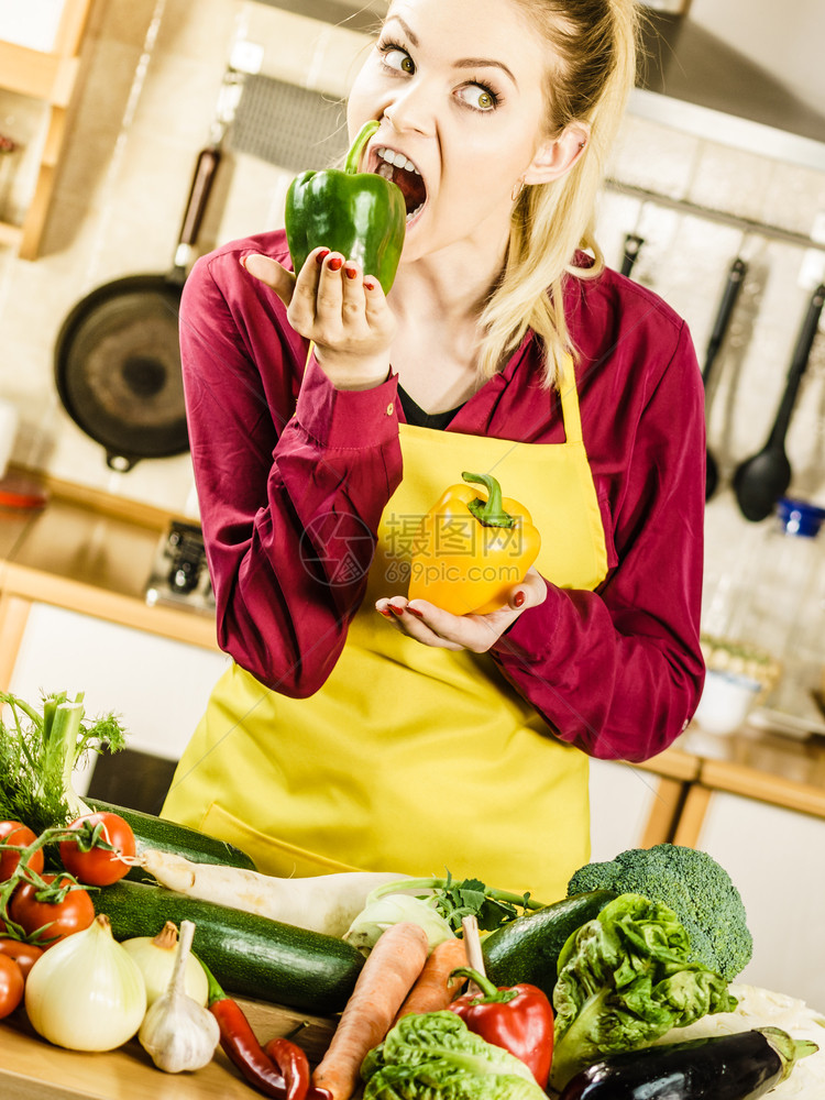 有趣的女人拿着胡椒美味的饮食蔬菜试图在厨房咬一口有趣的女人咬胡椒图片