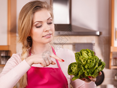 快乐的年轻女子做厨师拿着绿色生菜爱吃蔬的女即将做饭图片