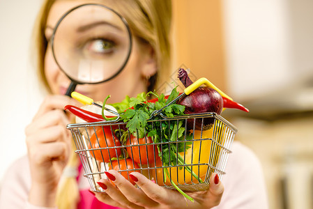 购物篮素材妇女使用放大玻璃槽许多彩蔬菜调查购物篮健康的饮食生活方式营养素食品寻找杀虫剂和化学品背景