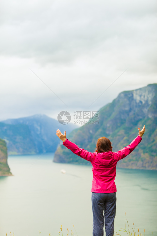 旅行概念自由游妇女快乐享受手举起来望着挪威的fjords山在挪威的Norwegian山码头举起手来的妇女图片