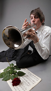一位年轻的爵士乐手肖像扮演他小号灰色背景爱情旋律图片