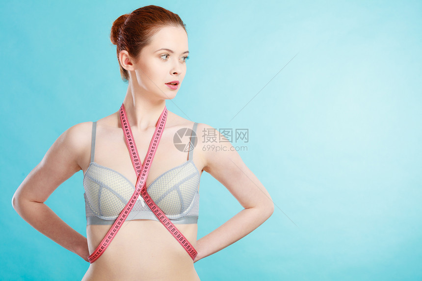 穿着内衣和测量胶带以控制其测量体重减肥概念的内衣瘦女孩对抗蓝色图片