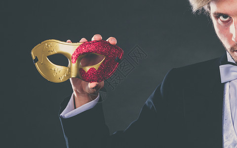 男手拿着红色金狂欢节面罩紧闭着黑暗男手拿着狂欢节面罩图片