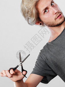 发型和发型年轻帅哥拿着理发师专用的剪子工具男人用剪刀织纹或变薄剪刀背景图片