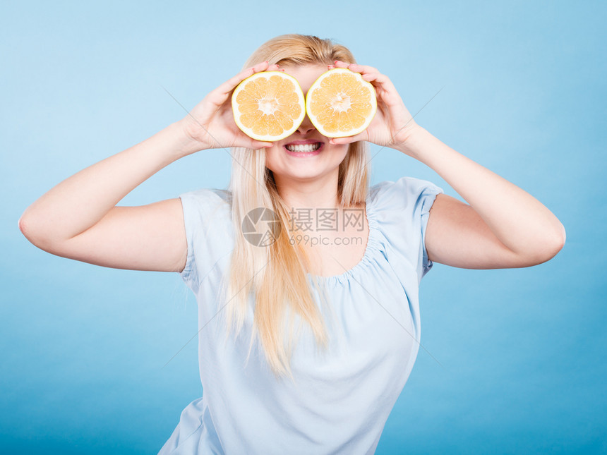 金发女少将两半黄葡萄果柑橘水握在手上蒙眼睛的蓝色健康饮食营养幸福的乐趣概念女孩用葡萄汁蒙在眼睛上图片