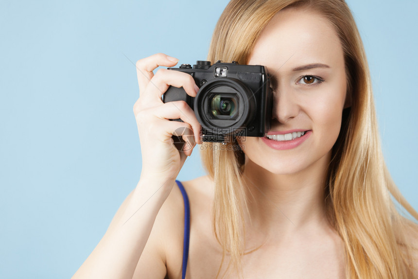 拍照片的女摄影记者拍照片的金发美女带着蓝背景相机的笑女金发美蓝背景相机的金发美女蓝色相机的金发美女图片