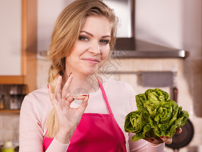 快乐的年轻女子做厨师拿着绿色生菜爱吃蔬的女即将做饭图片