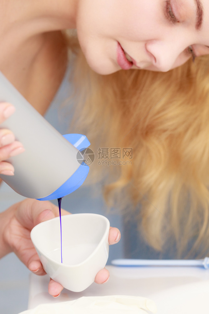 妇女将紫色头发染或洗水墨加到白碗中图片
