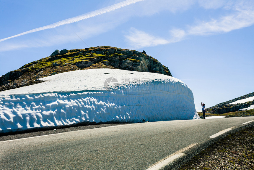 挪威Aurlandsfjellet山道高雪墙上拍摄照片的旅游女客图片