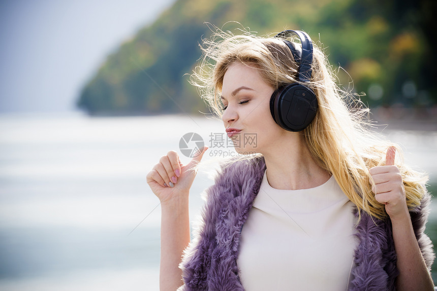 快乐的女子在户外听音乐穿着耳机的少女在散步时玩得开心图片