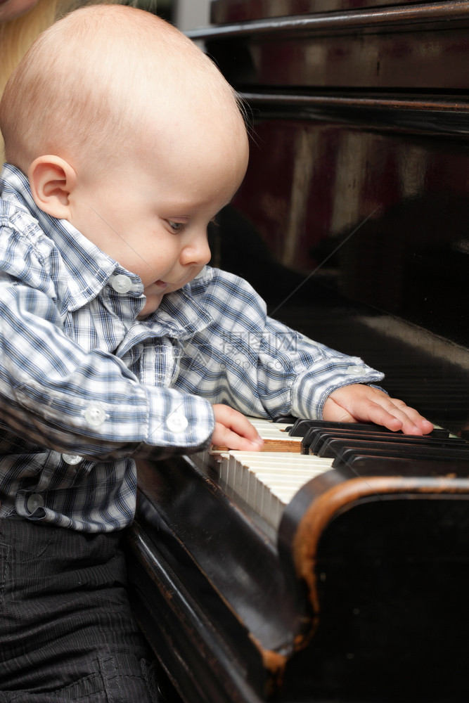 美丽的小男孩学习弹钢琴图片