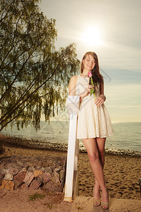 穿着短白色裙站着粉红色郁金香在海滩上自由度日图片
