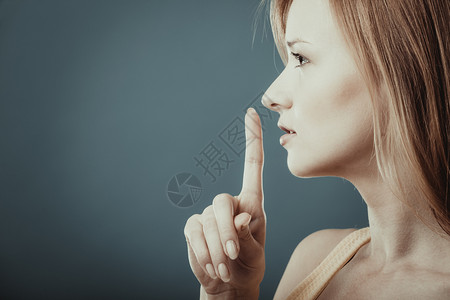 近身女在蓝背景下要求沉默或保密用手指在嘴唇上沉默手势要求或保密图片
