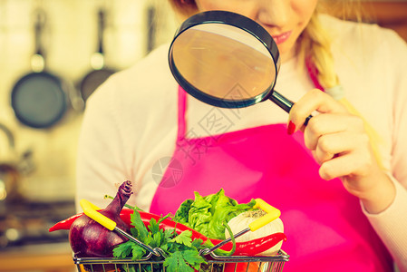 妇女使用放大玻璃槽许多彩蔬菜调查购物篮健康的饮食生活方式营养素食品寻找杀虫剂和化学品背景图片