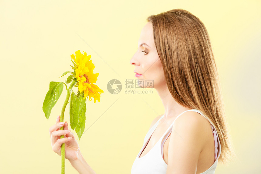 近距离的美貌女手上有向日葵站在黄色背景的侧面图片
