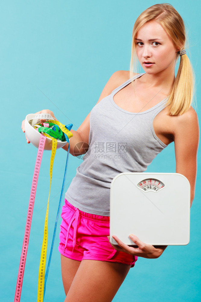 饮食健康饮食瘦身理念适合健身女孩拿着碗与许多彩色卷尺和体重秤图片